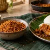Bowl of podi served with hot idlis and sesame oil