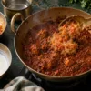 Plain onion-tomato base being added to an over-spiced curry