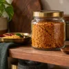 Closed glass jar of podi with a dry spoon on a pantry shelf