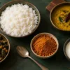 Bowls of rice, dal, curd and sabzi beside podi and a spoon