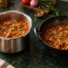 Indian masala curry cooking in a pressure cooker beside an open kadai