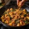 Podi being sprinkled over hot roasted potatoes and vegetables