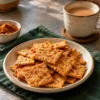 Golden baked atta crackers seasoned with podi beside a cup of chai