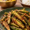 Roasted bhindi with a thin besan and podi coating on a green plate