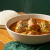 Cooked chicken meatballs in onion-tomato gravy served with rice.