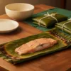Coconut-podi coated fish in an opened banana leaf parcel, with wrapped parcels nearby.