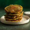Golden millet and mixed dal adai with a light podi sprinkle on a cream plate.