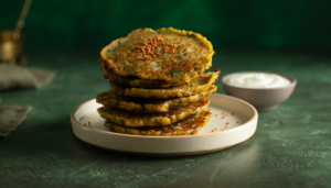 Golden millet and mixed dal adai with a light podi sprinkle on a cream plate.