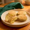 Golden crumb-coated raw banana cutlets with one cut open to show the filling.