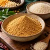 A bowl of dry podi beside short-grain idli rice, lentils and pepper