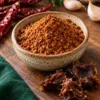 Dry podi in a bowl beside dried tamarind pulp, chillies and garlic
