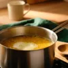 Yellow dal simmering in a saucepan with a pale layer of surface foam and ample headspace.